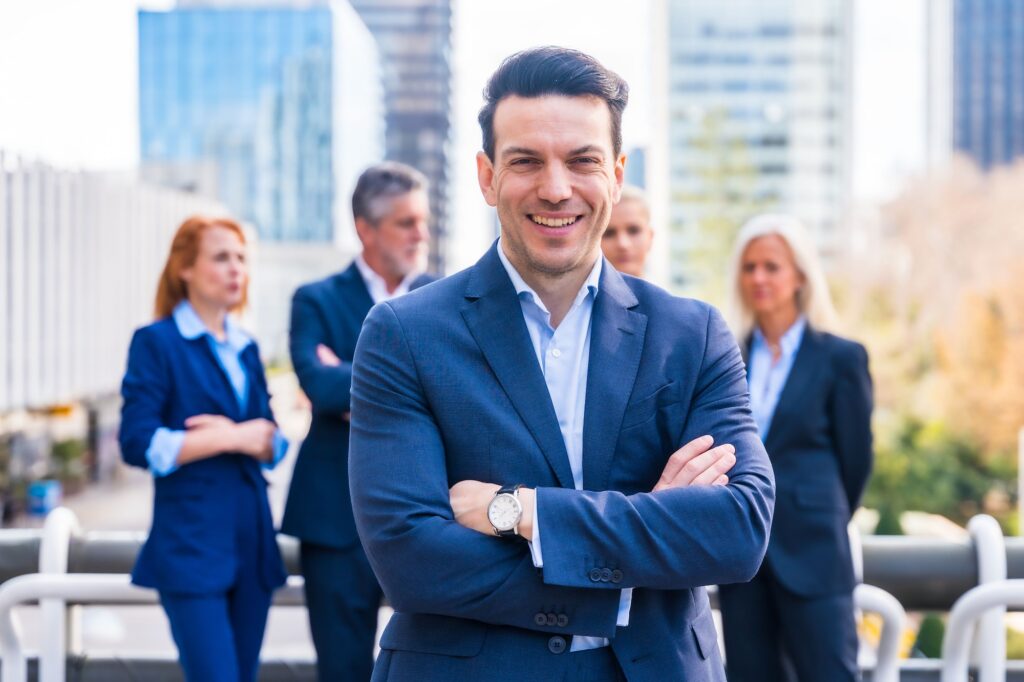 Caucasian businessman in a professional suit stands in front of a group of businesspeople